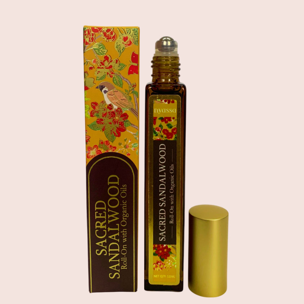Roll-on bottle of 'Sacred Sandalwood' with decorative packaging on a beige background