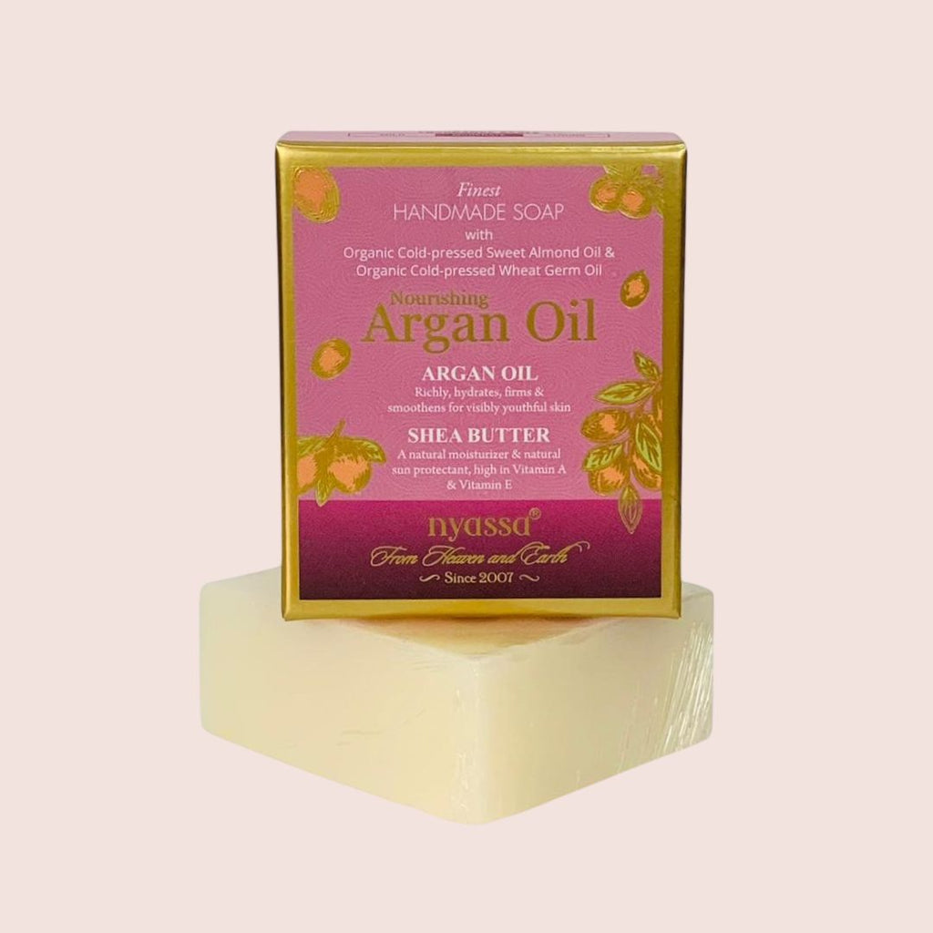 Bar of soap with a pink packaging box labeled 'Argan Oil' on a light pink background