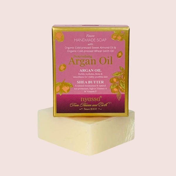 Bar of soap with a pink packaging box labeled 'Argan Oil' on a light pink background