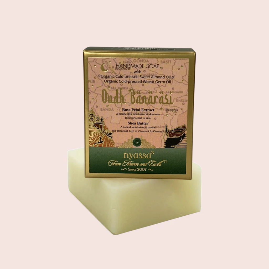 Handmade soap bar with a gold and green packaging on a light pink background
